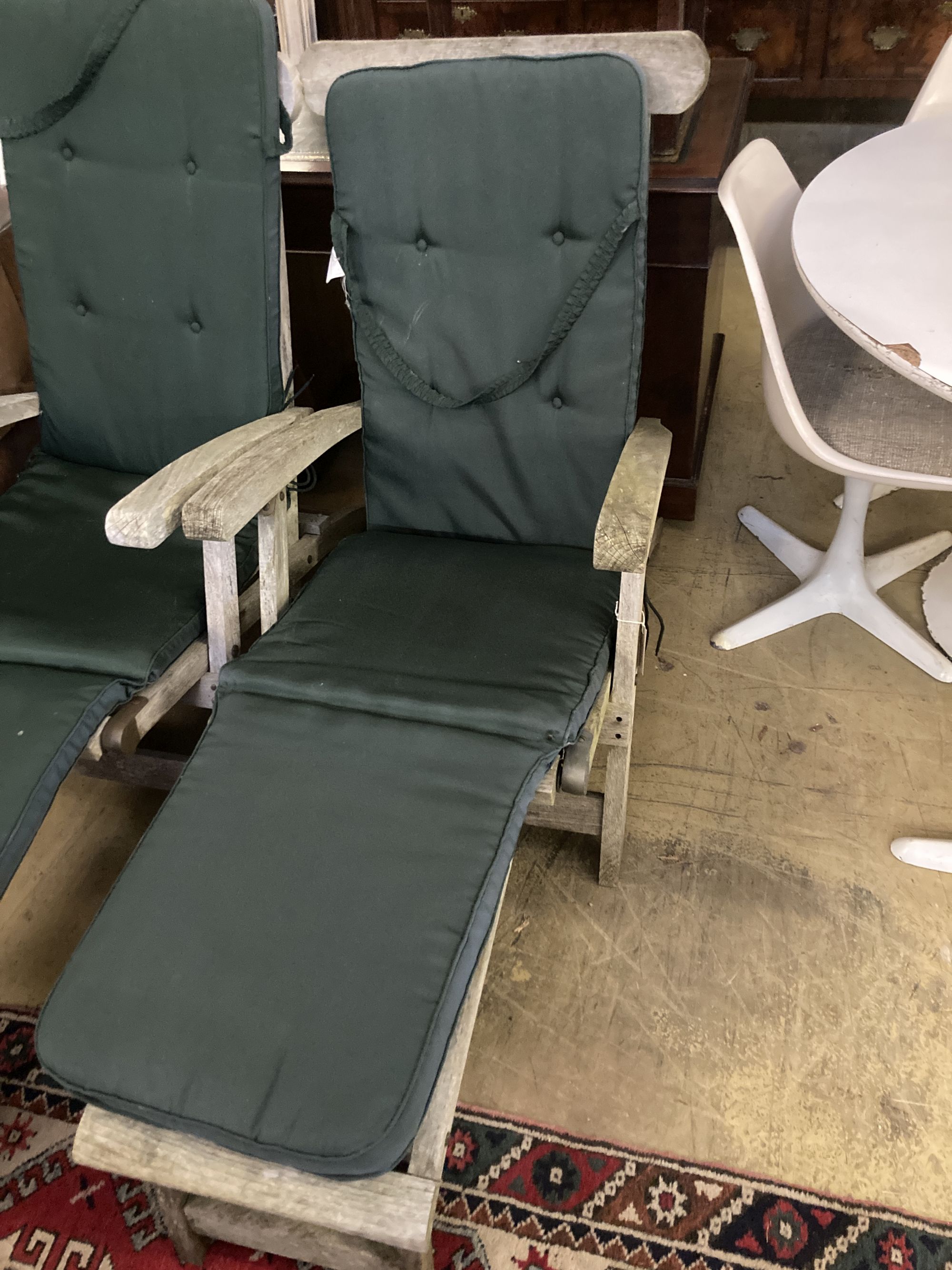A pair of weathered teak steamer garden chairs with cushions